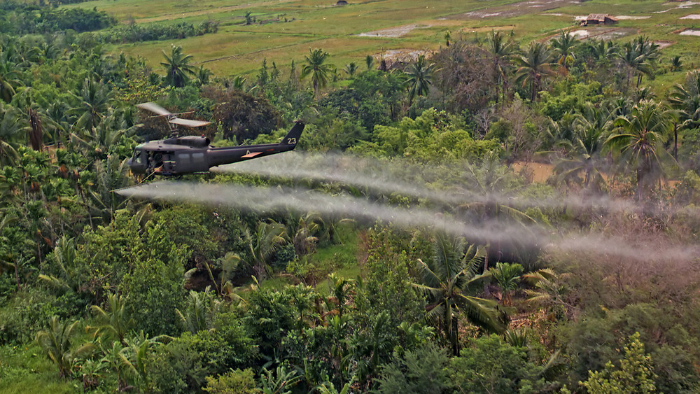 amerykański śmigłowiec rozpyla defolianty nad wietnamską dżunglą